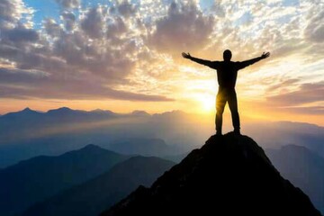 Silhouette of a Person on Mountain Peak at Sunrise