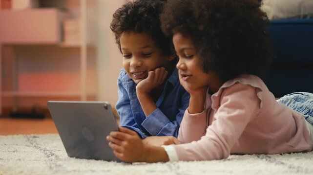 Joyful African American children watching funny videos on tablet, leisure time