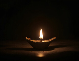 a lit candle in an ancient oil lamp on a dark background