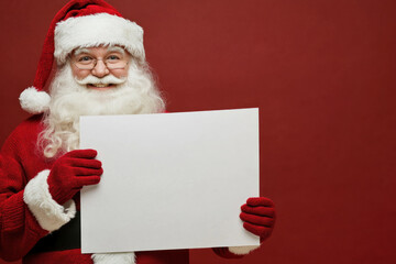 Naklejka premium Santa Claus holding a blank paper, ready for a special message.