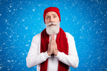 Photo of aged man arms palms together pleading look camera wear sweater isolated on blue color...