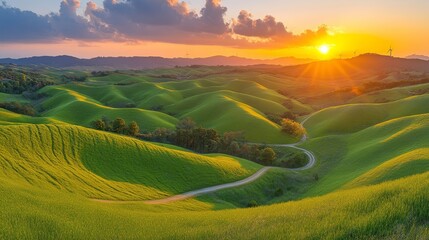 Una vista panorámica de colinas verdes con un camino serpenteante, iluminadas por los últimos rayos del sol en el horizonte.
