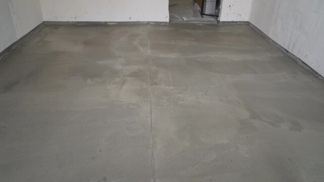 Freshly poured concrete is drying in an empty room, showcasing the renovation process in a residential space