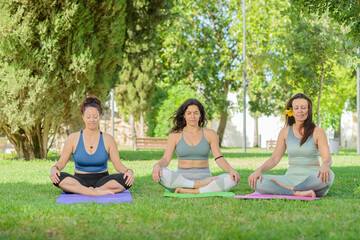 Three women meditating outdoors.