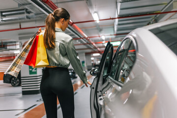 Young woman unlocking trunk of her car to put bags after shopping. © Mediteraneo
