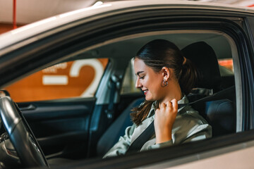 Young businesswoman putting a seatbelt on. Ready to drive off from his parking spot in an...