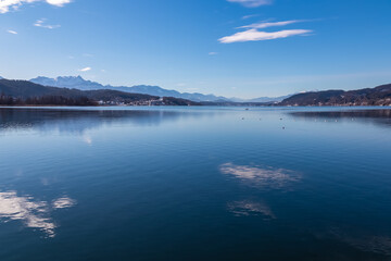 Panoramic view of alpine Lake Wörth surrounded by majestic mountains of Karawanks in Carinthia, Austria, Europe. Crystal-clear waters shimmer in sunlight. Viewing platform Hohe Gloriette, Pörtschach