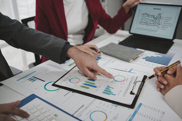 Business team analyzing financial documents pointing charts and graphs during a meeting in the office