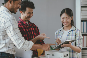 Architects team is discussing new project using digital tablet and model of a building