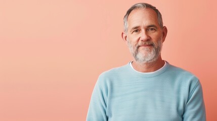 Obraz premium Mature Man with Salt and Pepper Hair in Light Blue Sweater on Coral Background for Portrait Design