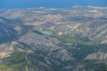 Aerial view of a mountainous landscape overlooking a tranquil bay in the distance on a clear day