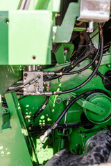 Farmer Mechanic Repairing Hydraulic Hose Under Combine Undercarriage, Wearing Yellow Gloves, Using Wrenches, Propped by Dual Tires, Agricultural Equipment Maintenance, Combine Harvester Repair