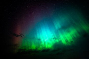 Colorful aurora borealis, beautiful beams of northern lights in the night sky against the background of stars.