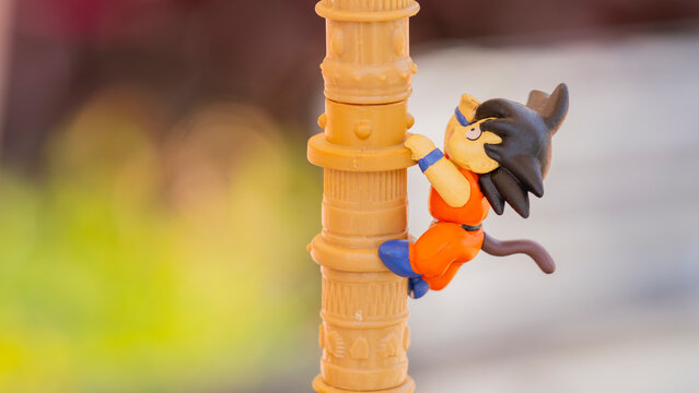 Close-up of a Goku figurine from Dragon Ball in his childhood form, climbing a pillar. Perfect for projects related to anime, collectibles, or nostalgic pop culture.