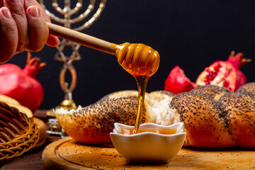 Honey dripping from a spoon on a table in Rosh Hashanah next to an apple, pomegranate