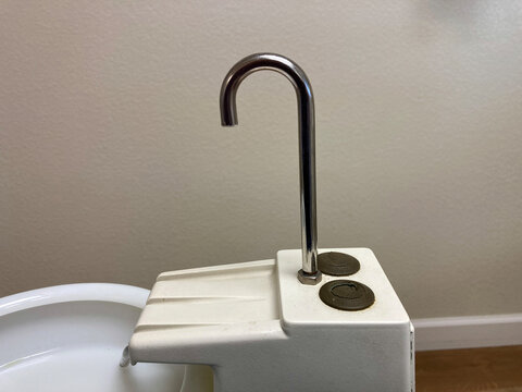 White dental spittoon with a sleek metal faucet and control buttons