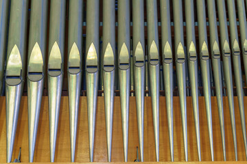 A large classical organ inside the Catholic Church.  A keyboard wind musical instrument. Pipe organ close-up.
