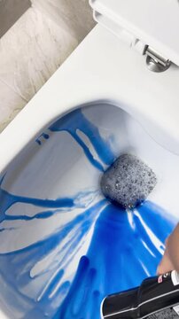 Clean white toilet bowl in a bathroom by blue cleaning liquid. High quality FullHD footage