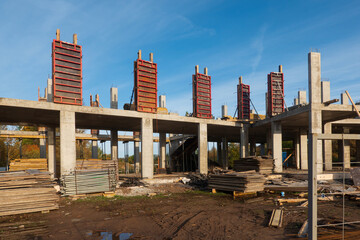 Construction of a building made of monolithic reinforced concrete. On the second floor there is a collapsible formwork. On the ground there are parts of the scaffolding. Background.