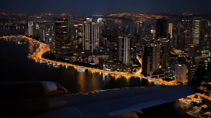 Night view of a vibrant city skyline illuminated by lights from an airplane window. - Powered by Adobe