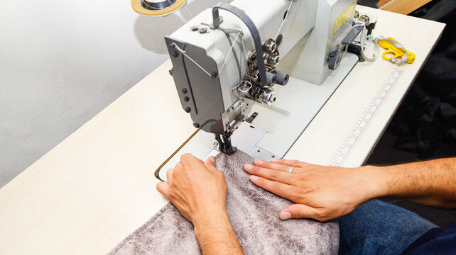 Man using industrial sewing machine with furniture fabrics. man sewing Industrial sewing machines. Closed angle, small company. Manufacture of furniture, upholstery, cushions. Business, industry.