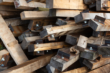 Nahaufnahme eines Stapels von aussortierten Bahnschwellen aus Holz, an denen Schrauben und Winkel montiert sind.