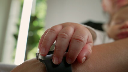 Close-up of baby’s hand gently resting on mother’s arm while sleeping, capturing a detailed and intimate moment between mother and child