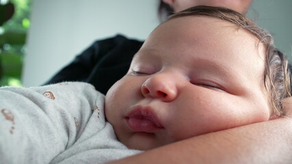 Baby peacefully asleep in mother’s arms, capturing a serene moment of rest in a nurturing home environment with soft, natural lighting