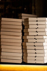 Stacks of neatly arranged pizza boxes create a warm, inviting atmosphere in a bustling pizzeria during the evening rush