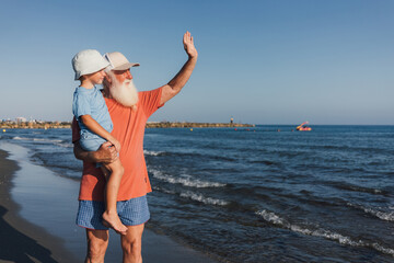 Grandfather Waving with Grandson on the Beach