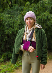 Young woman with broken arm slowly walking outdoors. Patient wears sling to support her arm....
