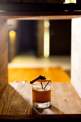 A cozy evening drink in a dimly lit bar showcasing a beautifully garnished cocktail with cinnamon and star anise