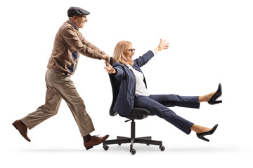 Elderly man pushing a businesswoman seated in an office chair