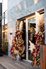 Unique autumn-inspired entrance decoration with pampas grass and colorful leaves in a modern urban setting