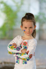 Little cute girl in Ukrainian traditional embroidered shirt and with Ukrainian flag on her cheek. Patriotic child concept