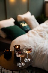 Cozy evening retreat with sparkling drinks, soft pillows, and a flickering candle in a beautifully arranged bedroom setting