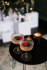Elegant champagne cocktails adorned with fresh strawberries beside flickering candlelight and festive decorations during a cozy winter evening