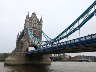 Obraz premium London, UK - 2023.05.13: Side view of Tower Bridge with Queen Elizabeth II Silver Jubilee repainting of blue and white over River Thames under a cloudy sky
