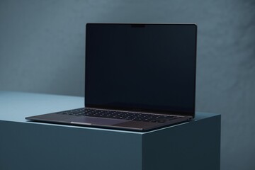 Sleek Laptop on a Blue Platform: A modern laptop with a black screen rests on a minimalist blue platform, creating a professional and sleek backdrop for your digital content.