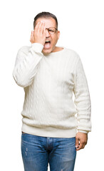 Middle age arab man wearing glasses over isolated background covering one eye with hand with confident smile on face and surprise emotion.