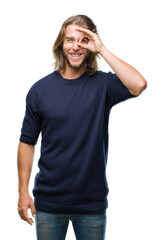 Young handsome man with long hair wearing winter sweater over isolated background doing ok gesture with hand smiling, eye looking through fingers with happy face.