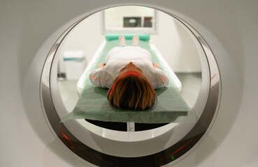 Woman patient lies on an MRI scanner bed, positioned for a diagnostic scan, with laser alignment...