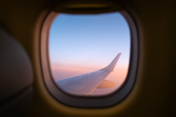 Naklejka premium View of airplane wing through window during flight at sunset - Landscape