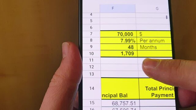 Man scrolling an excel sheet on the phone screen showing bank loan amortization table. Banking