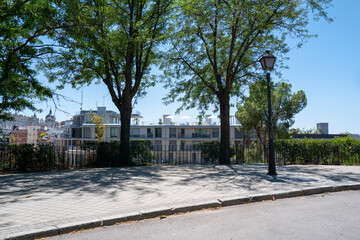 Rooftop pool view from a shaded path with trees and modern buildings in Madrid