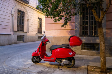 Red scooter parked on a quiet street with historic buildings in Madrid - Landscape