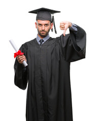 Young handsome graduated man holding degree over isolated background with angry face, negative sign showing dislike with thumbs down, rejection concept