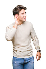 Young handsome man over isolated background smiling with hand over ear listening an hearing to rumor or gossip. Deafness concept.