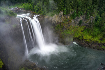 Fototapeta premium Snoqualmie Falls with lush greenery and mist in Washington State, USA. Snoqualmie Falls is a 268-foot waterfall on the Snoqualmie River between Snoqualmie and Fall City. Long exposure.