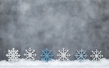 Decorative snowflakes on a gray background with a snowy base for winter-themed art and design projects